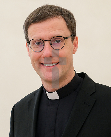 Porträtfoto von Weihbischof Dr. Martin Marahrens, im schwarzen Anzug und schwarzem Hemd mit Priesterkragen, freundlich lächelnd